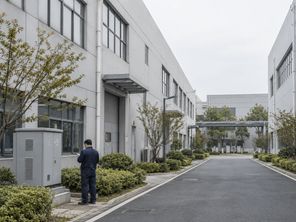 产业园厂房之间的道路,一名工作人员正在检查室外设备箱